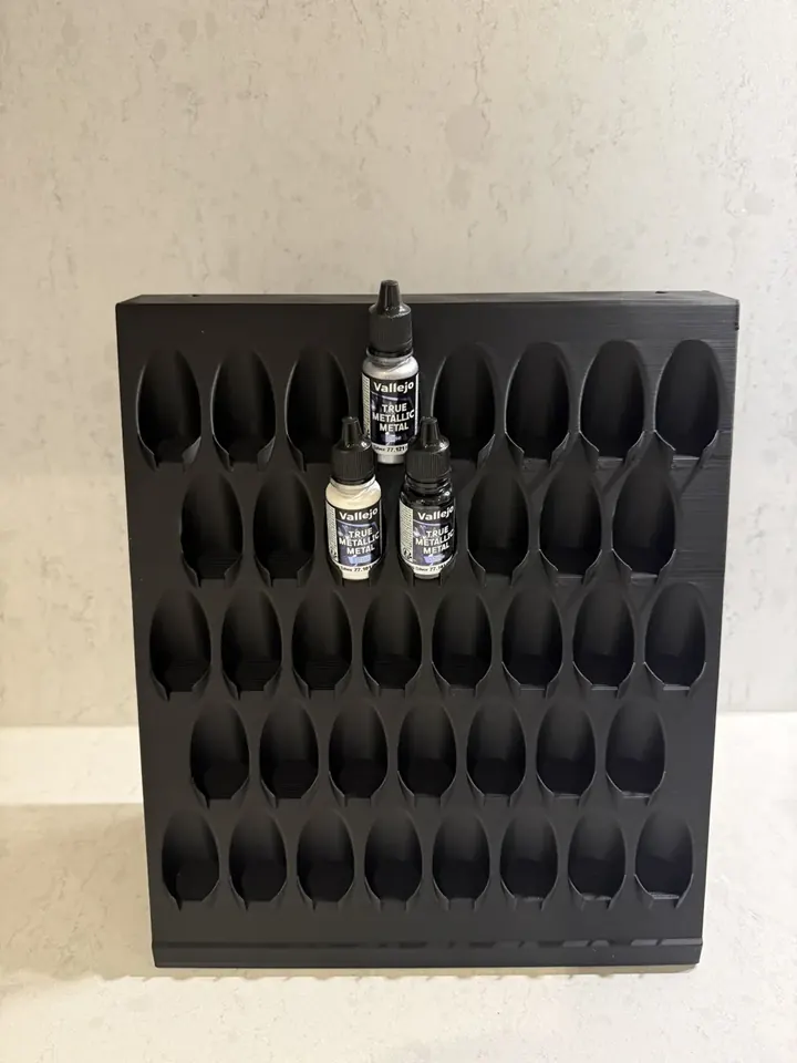 A black wall-mounted paint rack, printed and photographed in the Formada3D workshop